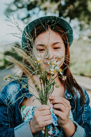 Woman in Blue Denim Jacket Holding Daisy Flowers