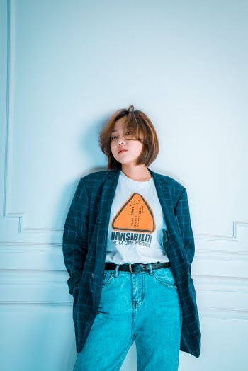 Woman In Blue Denim Jacket Standing Near White Wall · Free Stock Photo