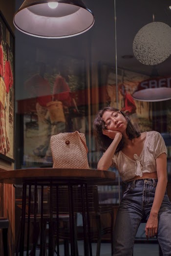 Woman in Blue Denim Pants Sitting on Brown Wooden Chair 