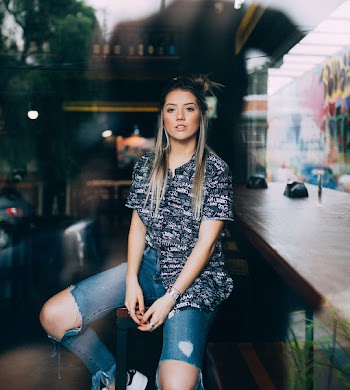 Woman In Blue Distressed Jeans Sitting On Bar Stool 