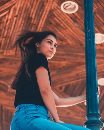 Woman in Blue Jeans Sitting Beside Pole