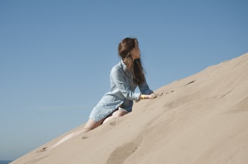 Woman in Blue Long Sleeve Shirt Sitting on Brown Sand