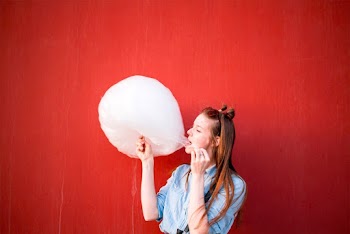 Woman In Blue Long Sleeved Shirt Eating Cotton Candy