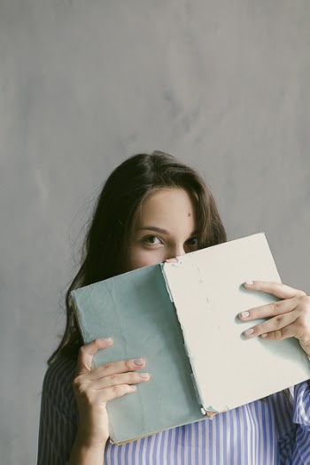 Woman in Blue Striped Flannel Shirt Holding a Book Indoors