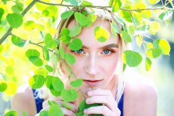 Woman in Blue Tank Top Hiding from Green Tree