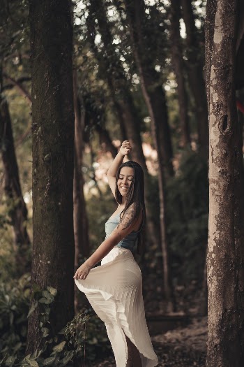Woman in Blue Tank Top Holds Her White Skirt in Forest