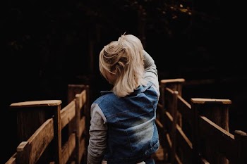 woman in blue vest holding hair