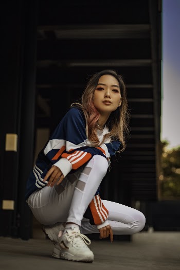 Woman in Blue, White and Red Jacket and White Pants Squatting on Floor