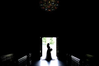 Woman in Bridal Gown in Front of Door in Silhouette