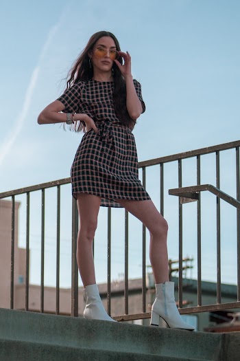 Woman in Brown and Black Checked Mini Dress Standing on Top of Stairs