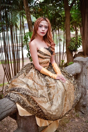 Woman in Brown and Black Sweetheart Neckline Dress Sitting on Railing