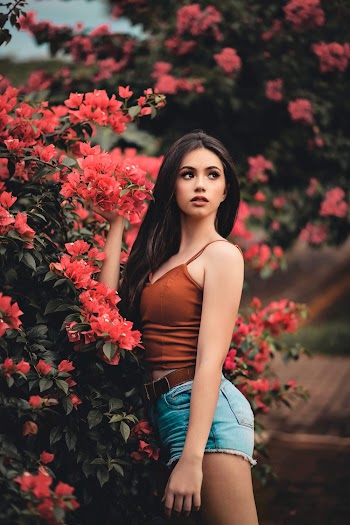 Woman in Brown Cami Top and Blue Denim Short Shorts Standing Beside Pink Flowering Bush