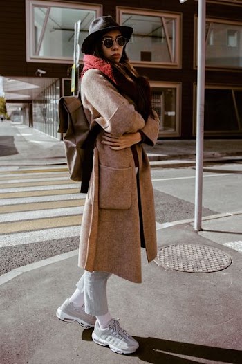 woman in brown coat near pedestrian during daytime