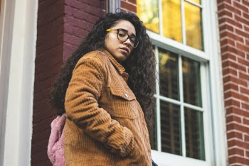Woman in Brown Corduroy Jacket in Front of White Sash Window