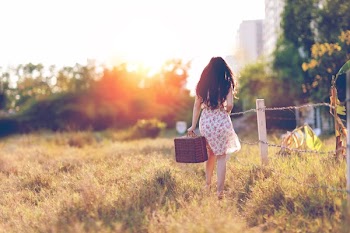 Woman in Brown Floral Dress Walking Near Fence