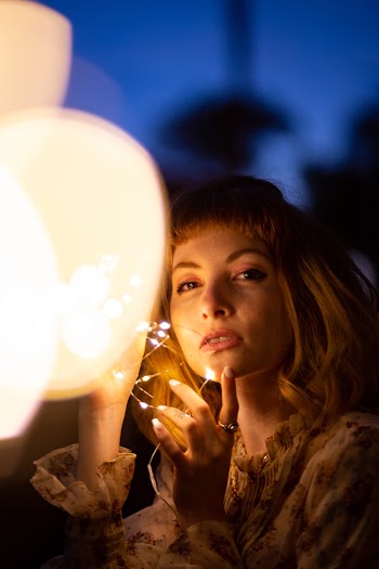 Woman in Brown Floral Top Standing and Holding String Lights