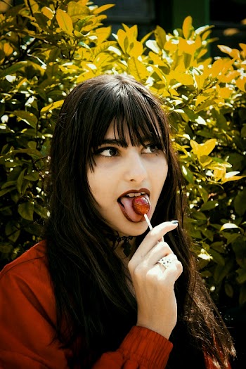Woman in Brown Jacket Eating Lollipop