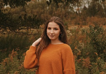 Woman in Brown Knit Sweater Standing Near Plants