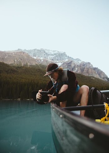 woman in brown shirt taking portrait on body of water