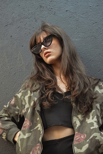 Woman In Camouflage Jacket Standing Beside Wall