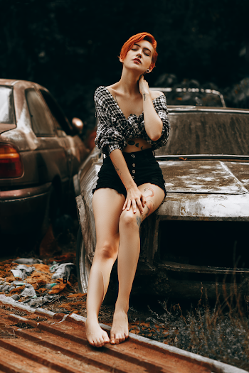 Woman in Crop Top and Black Short-shorts Sitting on Wrecked Car