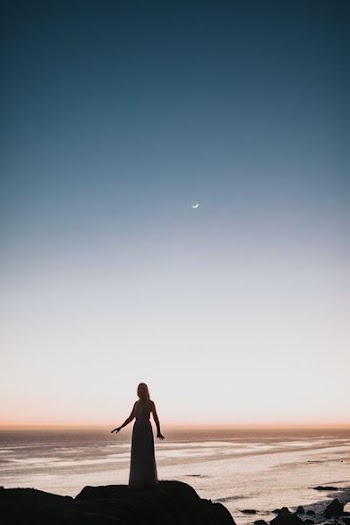 woman in dress standing near body of water