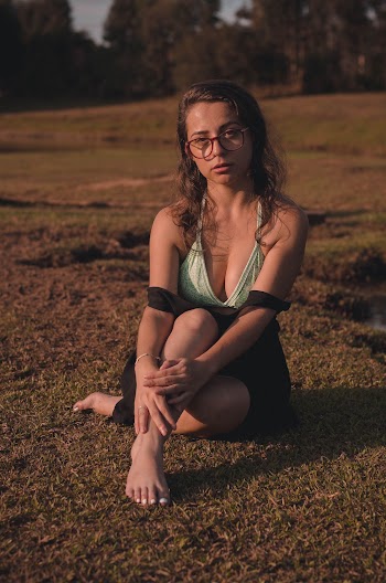 Woman in Eyeglasses Sitting on Ground