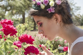 Woman in Floral Headdress Sniffing on Red Flowers