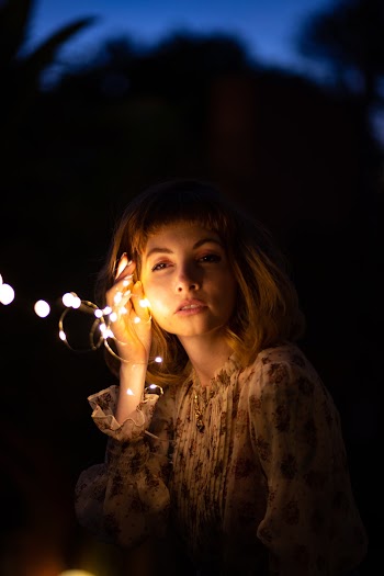 Woman in Floral Long-sleeved Top Holding String Lights at Night