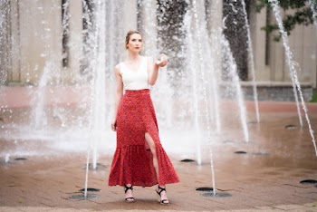 Woman in floral skirt  standing  near fountain.  