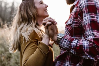 woman in front of man holding each hands each other near green trees