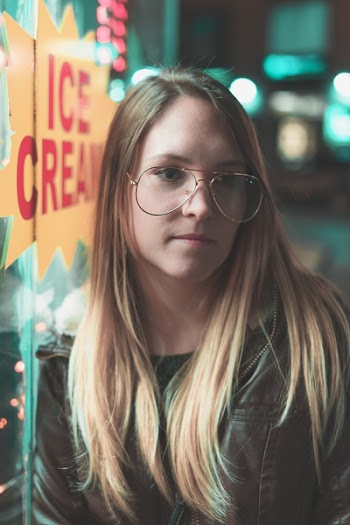 Woman in Gold Aviator-style Eyeglasses Leaning on Glass during Nighttime