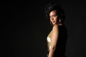 woman in gold sleeveless dress against black background