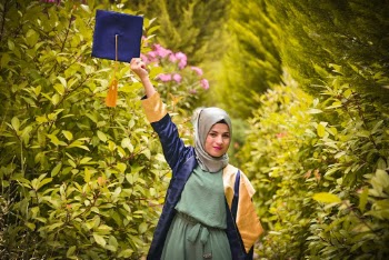 Woman in Graduation Robe Lifting Her Mortar over Her Head