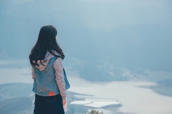 Woman in Gray and Blue Zip-up Hoodie Standing on the Cliff