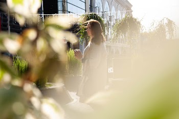 Woman in Gray Coat Standing Near Green Plants