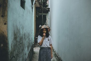 Woman in Gray Crew-neck Shirt in Middle of White and Teal Concrete Alley
