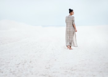 woman in gray dress walking on sand