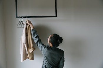 Woman in Gray Long Sleeve Shirt Holding Brown Long Sleeve Shirt