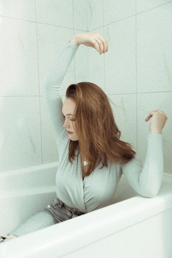 Woman in Gray Long-sleeved Shirt Sitting on Bathtub