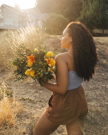 Woman in Gray Off-shoulder Top and Brown Shorts Holding Yellow Flower