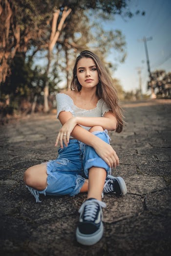 Woman in Gray Off-shoulder Top Sitting on Concrete Surface
