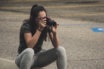 Woman in Gray Pants Sitting While Taking Photo