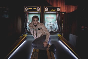 Woman in Gray Pullover Hoodie Sitting on Arcade Machine
