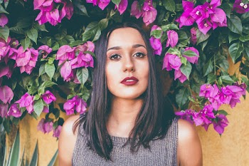 Woman in Gray Scoop-neck Sleeveless Top Standing in Front of Purple Flowers