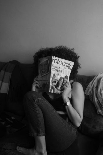 Woman in Gray Shirt and Blue Denim Jeans Sitting on Couch Reading Magazine · Free Stock Photo
