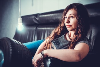 Woman in Gray Shirt Lying on Black Seat Sofa With Bulb Beside