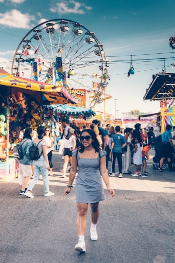 Woman in Gray Square-neck Mini Dress and White Sneakers Walking on Street With Ferris Wheel Background