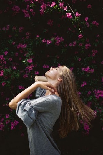 woman in gray top near pink flowers