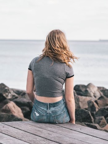 woman in gray top sitting on dock